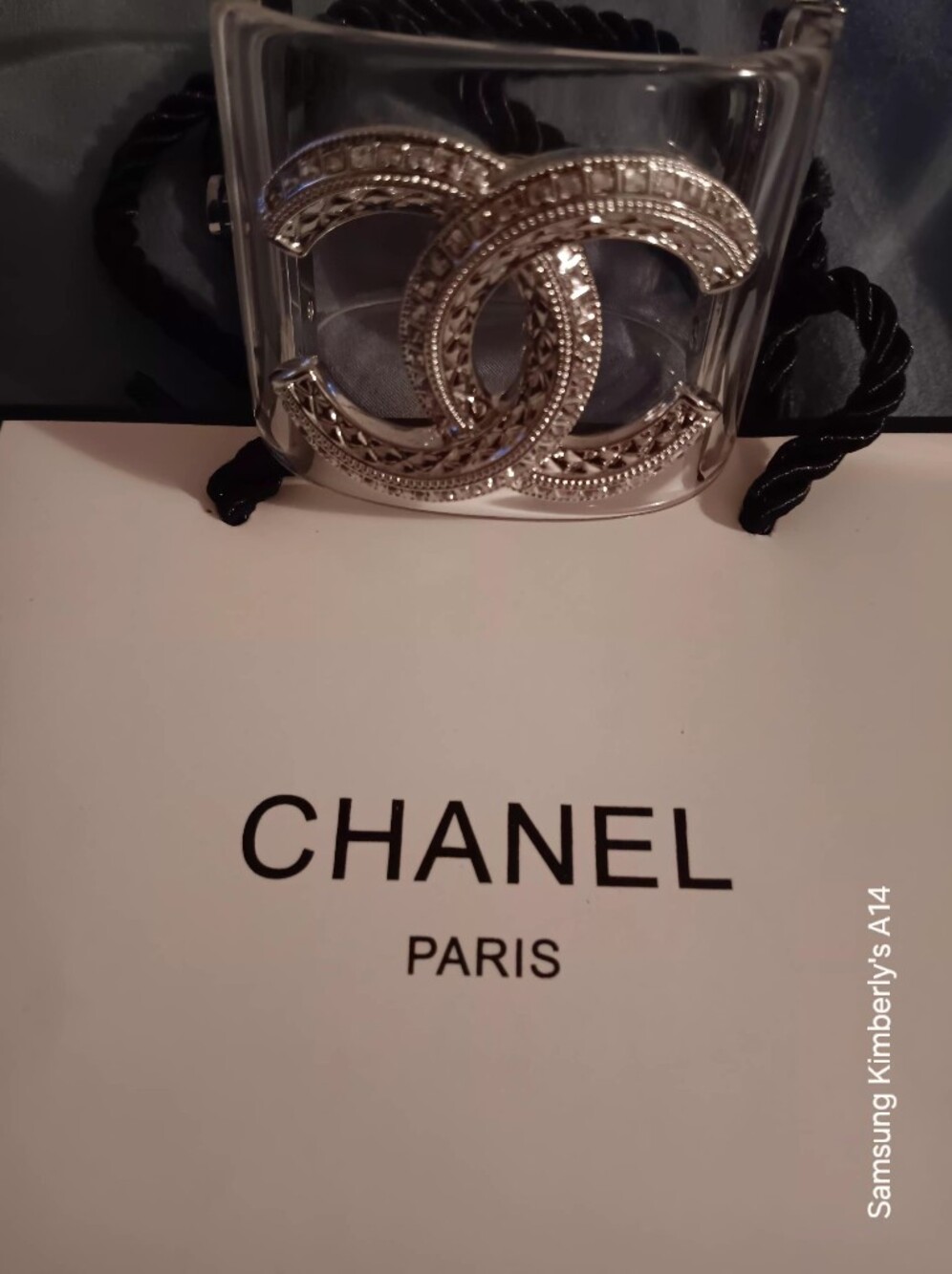 Chanel silver CC logo embedded with crystal baguette stones on a transpar